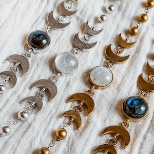 May include: Four necklaces featuring a series of crescent moon charms and round beads. Two necklaces are silver-toned with dark and clear round stones, while two are gold-toned with dark and clear round stones, all arranged in a repeating pattern.