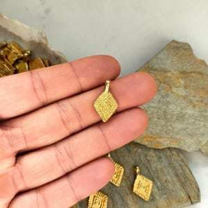 Puede incluir: Encantos de colgante de metal dorado con forma de diamante geom&eacute;trico y detalles intrincados. Los encantos tienen un bucle en la parte superior para sujetar a las joyas.