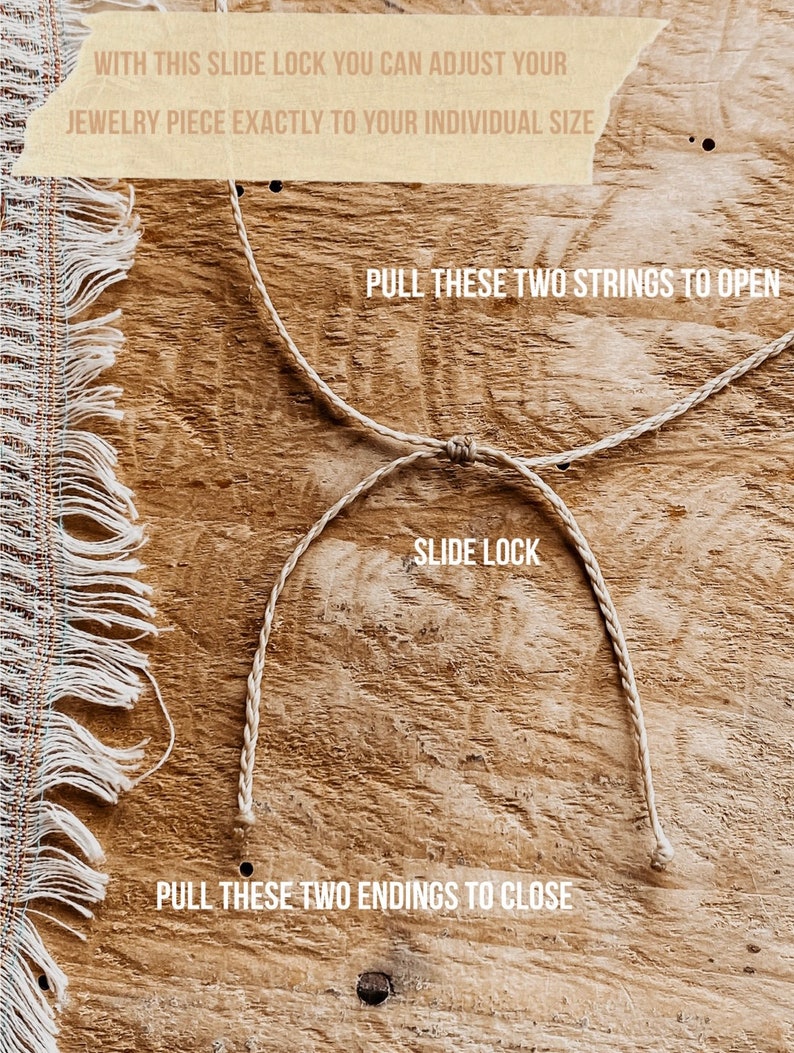 May include: A beige braided cord jewelry slide lock mechanism featuring text instructions: WITH THIS SLIDE LOCK YOU CAN ADJUST YOUR JEWELRY PIECE EXACTLY TO YOUR INDIVIDUAL SIZE, PULL THESE TWO STRINGS TO OPEN, SLIDE LOCK, PULL THESE TWO ENDINGS TO CLOSE.