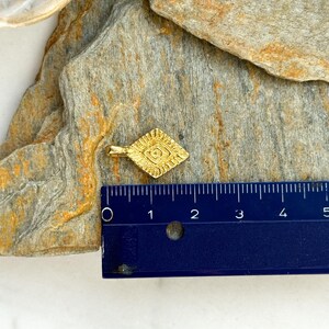 Puede incluir: Un colgante de color dorado en forma de diamante con un dise&ntilde;o intrincado. El colgante mide aproximadamente 2,5 cm de largo.
