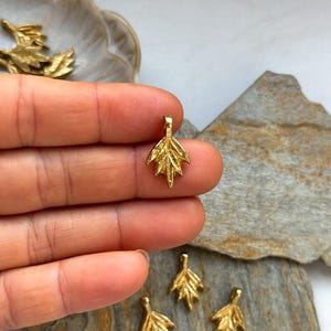 以下が含まれることがあります： 繊細なデザインのゴールドリーフチャームペンダント。チャームは小さく繊細で、ジュエリーに自然のタッチを加えるのに最適です。