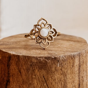 Puede incluir: Anillo de oro con una piedra blanca engastada en un delicado diseño floral.