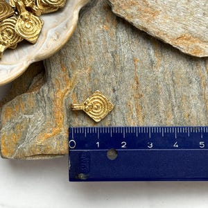 K&ouml;nnte beinhalten: Goldfarbener Metallanh&auml;nger mit Spiraldesign. Der Anh&auml;nger hat die Form eines Diamanten und ist etwa 2,5 cm lang. Der Anh&auml;nger wird neben einem Lineal zur Gr&ouml;&szlig;enreferenz gezeigt.