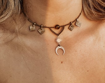 May include: A gold choker necklace with a crescent moon and star pendant. The necklace has small, decorative charms hanging from it.