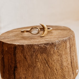 Puede incluir: Un anillo de oro con un diseño de media luna y una piedra preciosa transparente en forma de lágrima.