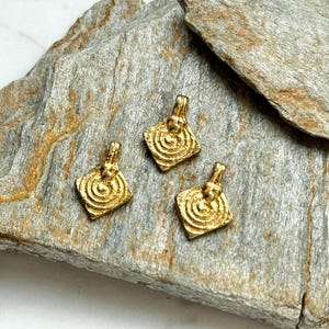 K&ouml;nnte beinhalten: Drei goldfarbene Metallanh&auml;nger mit quadratischer Form und einem Spiraldesign. Die Anh&auml;nger haben eine &Ouml;se oben zum Anbringen an einer Kette oder Schnur.