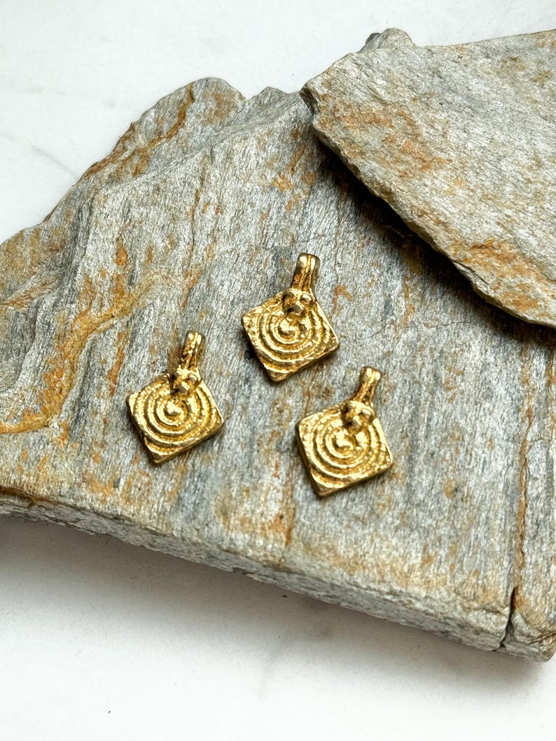 K&ouml;nnte beinhalten: Drei goldfarbene Metallanh&auml;nger mit quadratischer Form und einem Spiraldesign. Die Anh&auml;nger haben eine &Ouml;se oben zum Anbringen an einer Kette oder Schnur.