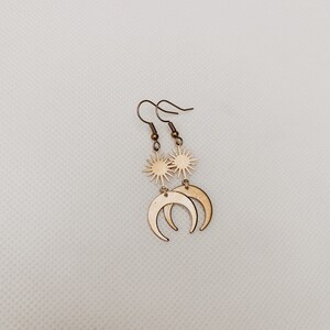 May include: Gold tone earrings with a sun and crescent moon design.