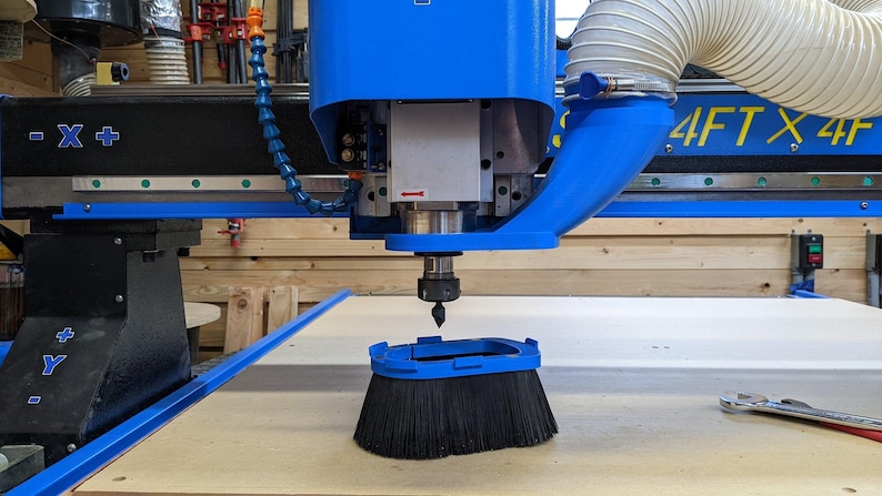 May include: A blue CNC router with a dust collection system and a black brush attached to the spindle. The router is labeled "4FT X 4FT".