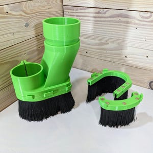 Puede incluir: Sistema de recolección de polvo de plástico verde con cerdas negras. El sistema incluye una unidad principal con un accesorio de manguera y dos unidades más pequeñas con cerdas negras.