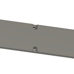 Puede incluir: Un objeto rectangular gris con extremos redondeados y múltiples agujeros. El objeto, con una superficie lisa, parece estar hecho de un material sólido. El diseño sugiere un componente o parte de un producto más grande.
