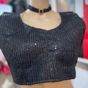 May include: A black sequined crop top with a v-neckline and a black choker necklace with a gold accent.