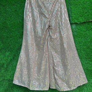 May include: Wide-leg pants with a brown base covered in iridescent sequins. The pants have a high waist and a relaxed fit.