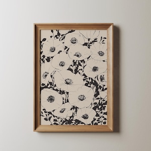 K&ouml;nnte beinhalten: Ein gerahmter Schwarzwei&szlig;druck mit einem floralen Design, das eine Ansammlung von Mohnblumen zeigt. Die Blumen sind in Schwarz auf einem cremefarbenen Hintergrund umrandet.
