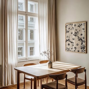 K&ouml;nnte beinhalten: Ein Esstisch aus Holz mit vier St&uuml;hlen, in einem Raum mit wei&szlig;en Vorh&auml;ngen und einem gerahmten Schwarzwei&szlig;-Blumenbild an der Wand.