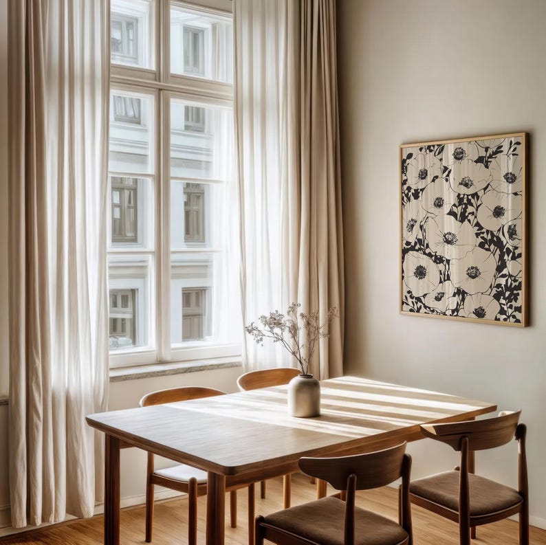 K&ouml;nnte beinhalten: Ein Esstisch aus Holz mit vier St&uuml;hlen, in einem Raum mit wei&szlig;en Vorh&auml;ngen und einem gerahmten Schwarzwei&szlig;-Blumenbild an der Wand.