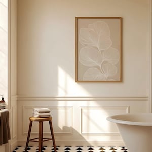 Puede incluir: Un ba&ntilde;o blanco con una ba&ntilde;era independiente, un taburete de madera con toallas y una impresi&oacute;n enmarcada de un dibujo de l&iacute;nea blanca de una planta sobre un fondo beige.