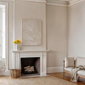 Puede incluir: Una repisa de chimenea blanca con una impresi&oacute;n de lienzo enmarcada en blanco de un dise&ntilde;o floral estilizado encima. La chimenea tiene un hogar de ladrillo y un hogar de le&ntilde;a. Una cesta de mimbre se encuentra en el suelo frente a la chimenea.