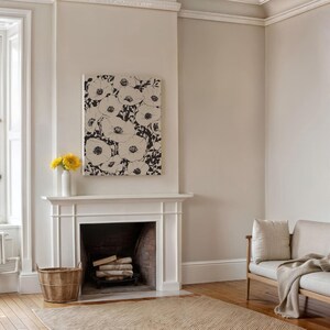 K&ouml;nnte beinhalten: Ein wei&szlig;er Kaminsims mit einem schwarz-wei&szlig;en floralen Leinwandbild dar&uuml;ber. Der Kamin hat einen Backstein-Innenraum und ein Holzfeuer. Ein Weidenkorb steht auf dem Boden vor dem Kamin.