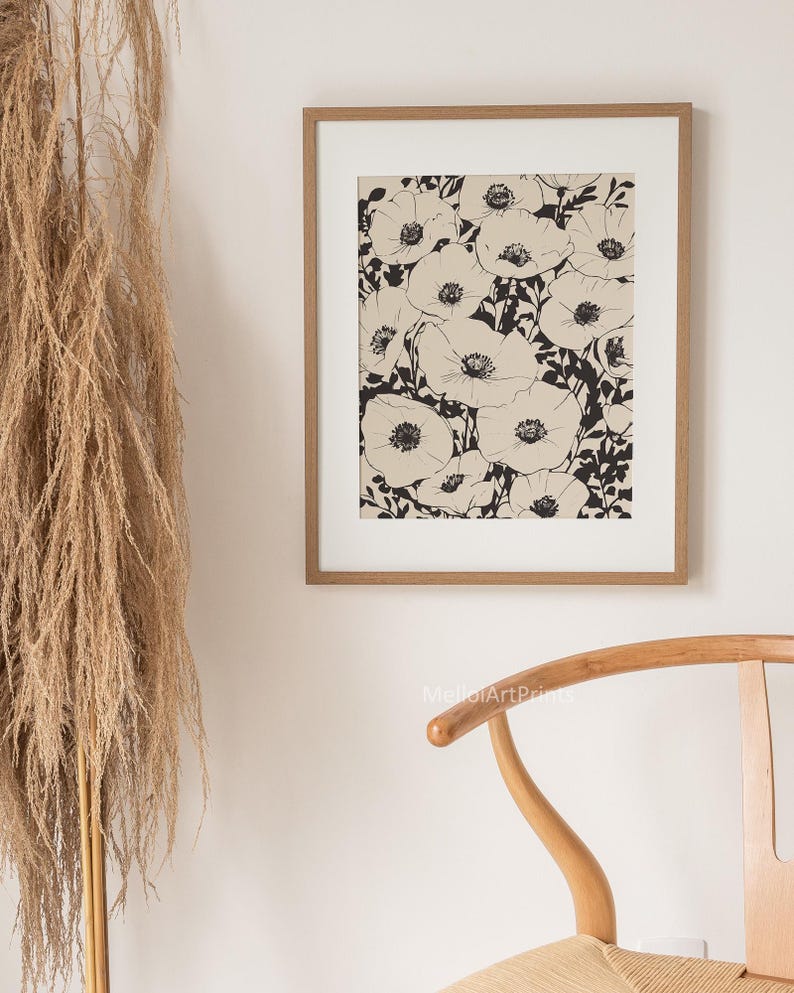 K&ouml;nnte beinhalten: Ein Schwarz-Wei&szlig;-Linienkunst-Druck eines floralen Designs mit einer Ansammlung von Mohnblumen. Der Druck ist in einem hellbraunen Holzrahmen gerahmt und h&auml;ngt an einer wei&szlig;en Wand.