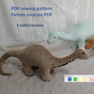 Könnte beinhalten: Drei Plüsch-Dinosaurier-Spielzeuge in Beige- und Hellblautönen werden gezeigt. Der Text "PDF sewing pattern" und "2 tailles inclues" ist sichtbar. Ein Schwierigkeitsgrad-Indikator ist ebenfalls vorhanden.
