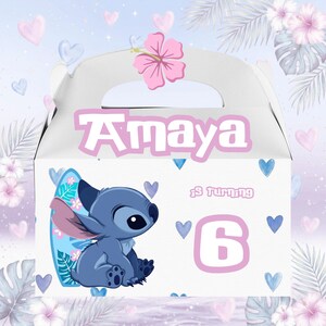 May include: White party favor box featuring the name "Amaya" in pink, a cartoon character, and the number "6". The box is decorated with hearts, flowers, and a surfboard. A pink hibiscus flower is on top.