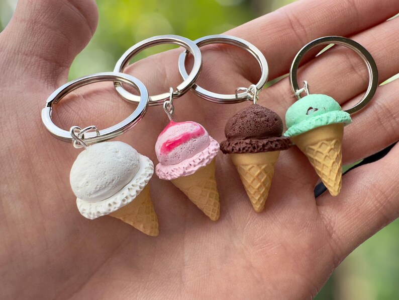 K&ouml;nnte beinhalten: Vier Schl&uuml;sselanh&auml;nger in Form von Eiswaffeln mit verschiedenen Geschmacksrichtungen: wei&szlig;, rosa und wei&szlig;er Swirl, braun und gr&uuml;n. Jeder Schl&uuml;sselanh&auml;nger ist an einem silbernen Schl&uuml;sselring befestigt.