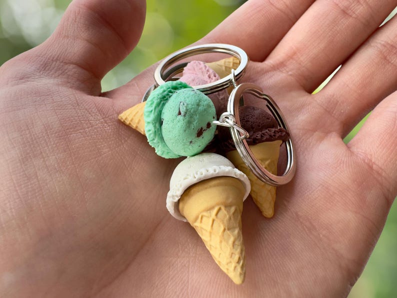 K&ouml;nnte beinhalten: Ein Schl&uuml;sselanh&auml;nger mit drei Miniatur-Eiswaffeln mit verschiedenen Geschmacksrichtungen: Minz-Schokoladen-Chip, Vanille und Schokolade. Die Waffeln sind an einem silbernen Schl&uuml;sselring befestigt.