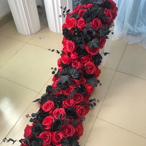 Pode incluir: Uma longa guirlanda de rosas artificiais vermelhas e pretas com folhas verdes. A guirlanda é perfeita para um casamento ou outro evento especial.