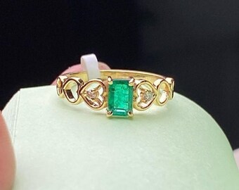 May include: A gold ring with a green emerald gemstone and small diamonds set in a heart-shaped design.