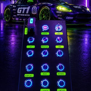 May include: A black rectangular button box control panel with illuminated blue circular buttons and a toggle switch. The panel features green labels including Engine, Map, TC1, Brake Bias, Abs, Display, Rain, Wipers, Lights, and Limiter.