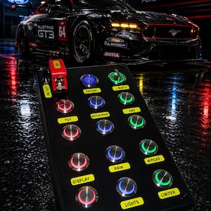 May include: A black rectangular button box controller featuring a red toggle switch labeled ON/OFF and multiple illuminated push buttons with yellow labels including ENGINE, MAP, TC1, BRAKE BIAS, ABS, RAIN, WIPERS, DISPLAY, LIGHTS, and LIMITER.