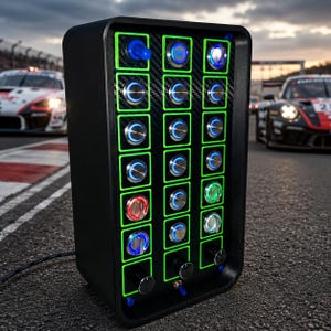 May include: A black rectangular button box featuring a carbon fiber texture panel with three vertical columns of illuminated push buttons and rotary knobs. The buttons are framed in bright green borders, with various blue, red, and white LED lights.