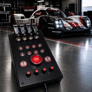 May include: A black control panel featuring four top-mounted toggle switches, a central red Engine Start button, multiple smaller silver and red rotary knobs, and additional push buttons, all arranged on a slanted rectangular housing unit.