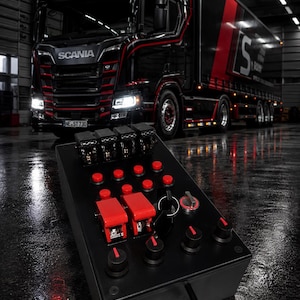 May include: A black control box featuring a row of four toggle switches, six small red push buttons, two large red lever switches, a key ignition, and four black rotary knobs. The device is connected by a black cable and has a matte finish.