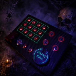 May include: A black carbon fiber button box controller featuring a grid of twelve illuminated red push buttons, three rotary dials, and a large circular dial labeled BRAKE BIAS with R and F indicators. An ENGINE START button is also present.
