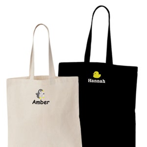May include: Two personalized tote bags. One is white with a penguin and the name "Amber" embroidered on it. The other is black with a yellow rubber duck and the name "Hannah" embroidered on it.