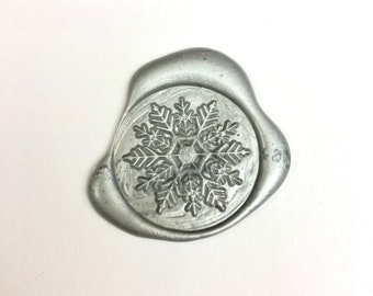May include: A silver wax seal featuring a snowflake design.