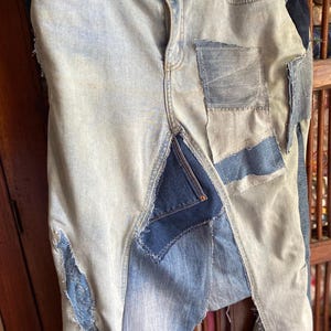 Könnte beinhalten: Hellblaue Jeans aus Denim mit Patches und Destroyed-Details. Die Jeans hat eine hohe Taille und ein gerades Bein.