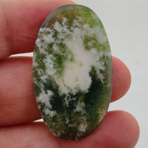 May include: Oval shaped green and white agate cabochon with a swirling pattern. The stone has a white center with green and white swirls around it.