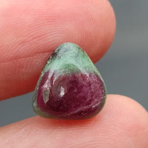 Könnte beinhalten: Ein grüner und rosafarbener Edelstein-Cabochon in dreieckiger Form.