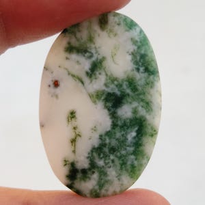 May include: Oval shaped green and white agate cabochon with a red fleck. The stone has a swirling pattern of green and white.