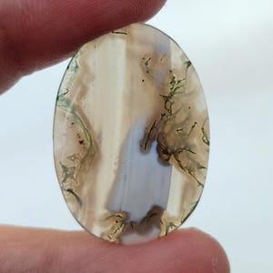 May include: Oval shaped agate cabochon with a white, brown, and green moss agate pattern.