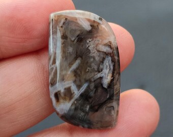 May include: A cabochon cut agate gemstone with a brown, white and grey pattern. The stone has a smooth, polished surface.