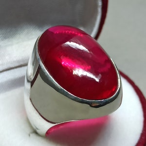 Puede incluir: Un anillo de plata con una gran piedra preciosa roja ovalada.