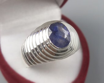 May include: A silver ring with a blue gemstone set in a textured band.