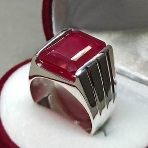 Peut inclure: Une bague en argent avec une grande pierre rouge de forme carrée.