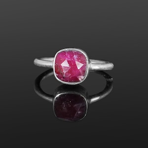 以下が含まれることがあります： 赤い宝石がついた銀の指輪。宝石は正方形で、ファセットカットされています。