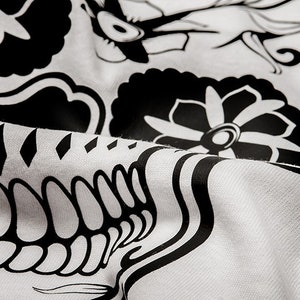 May include: Black and white fabric with a floral design. The fabric has a textured surface and is folded in the center.