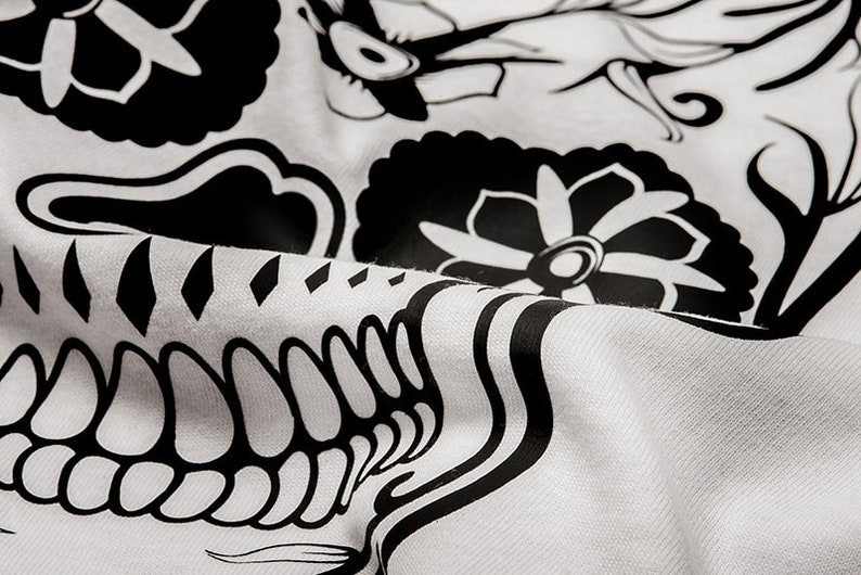 May include: Black and white fabric with a floral design. The fabric has a textured surface and is folded in the center.